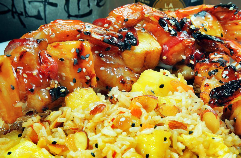 Shrimp Brochette · Large shrimp wrapped in applewood bacon, skewered with pineapples, grilled and glazed with Hawaiian teriyaki sauce. Served with tropical fried rice. (Contains Almonds)