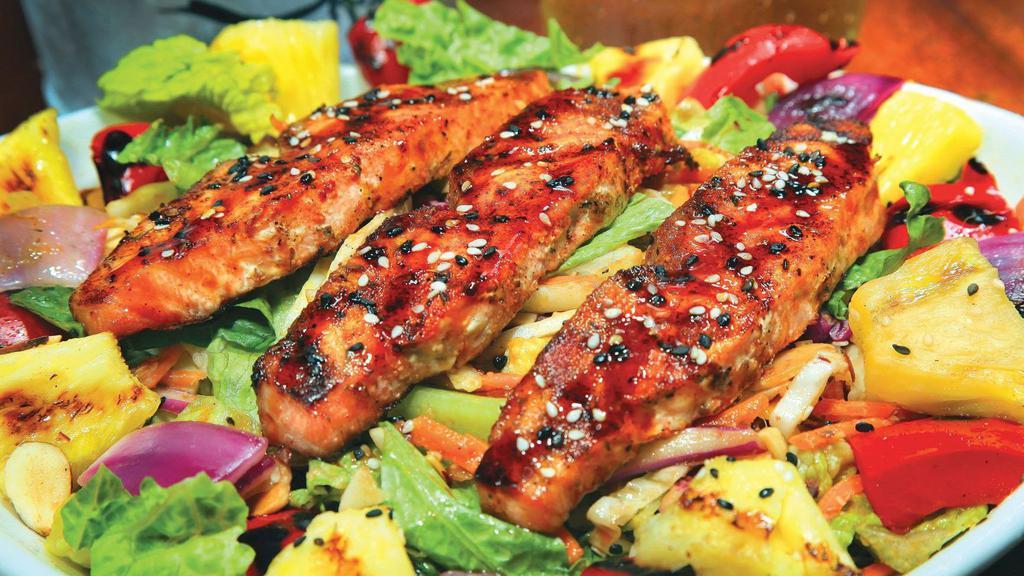 Asian Salmon Salad · Grilled salmon over mixed greens with carrots and cabbage tossed in a ginger dressing topped with fire roasted red peppers, red onion, grilled pineapple chunks, sliced almonds, green onions and drizzled with a sweet Asian sauce.
