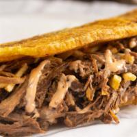 Patacon Carne · Green plantain, shredded beef, Guayanes cheese, homemade sauce and potato sticks. Fried gree...