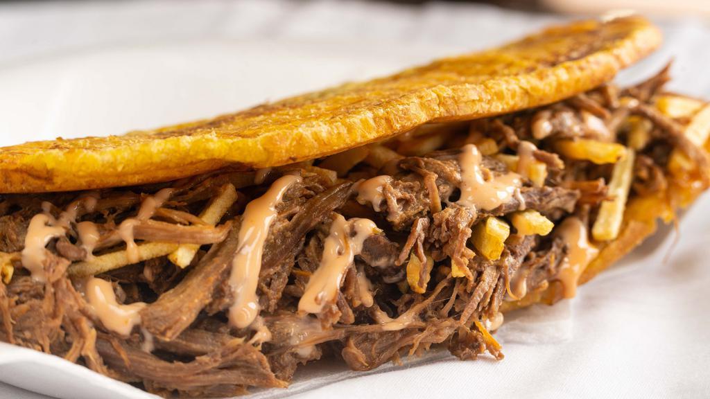Patacon Carne · Green plantain, shredded beef, Guayanes cheese, homemade sauce and potato sticks. Fried green plantain.