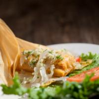 Tamal Cubano Especial · Home-style corn meal laced with seasoned pork, wrapped in a corn husk, topped with tender pi...
