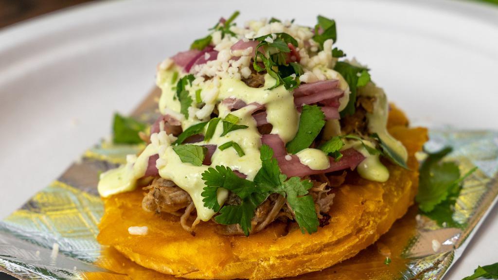 Tostones · Most popular. Three pieces. Tostones fried green plantains topped with ropa vieja shredded beef, pickled onions, cotija cheese, guacamole, and jalapeño aioli.