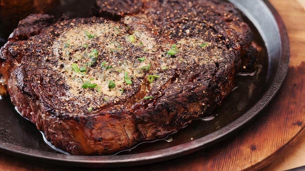 Pecan-Smoked Caramelized Prime Rib, 16 Oz* | Gf · Choice Ribeye seasoned and slow smoked in pecan wood, crusted and seared, topped with steak butter. Served with an au jus and creamy horseradish
