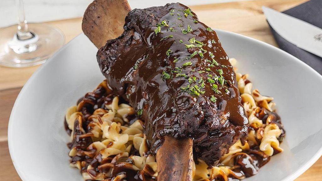 Tomahawk Braised Beef Short Ribs* | Gf · Fork tender long bone beef short ribs, braised for three hours with ancho chiles, and served on buttered egg noodles with Parmesan cheese