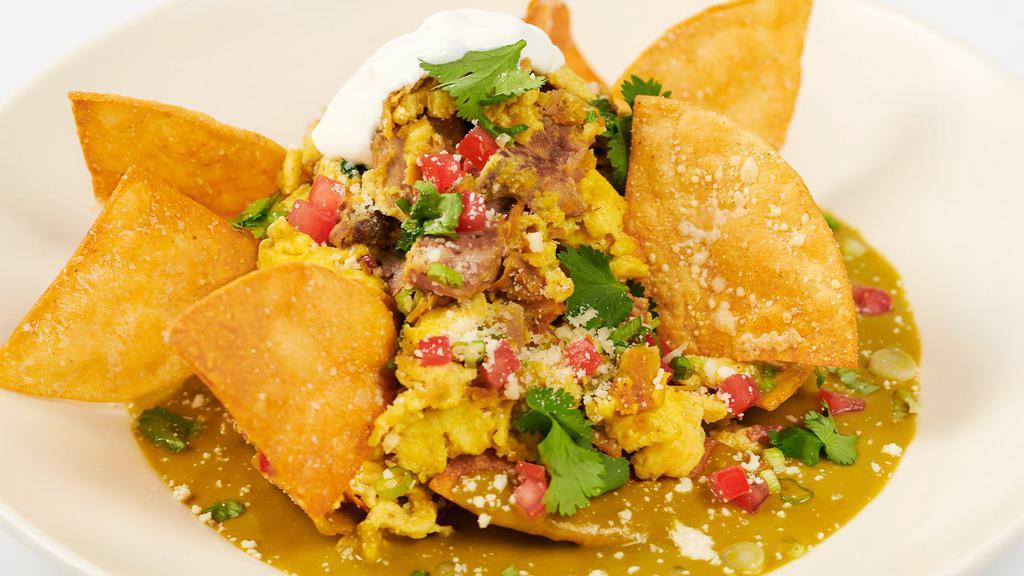 Green Chilaquiles With Carnitas & Eggs · Tender Slow-Cooked Pork with Roasted Poblano Peppers, Cheese, Onions, Cilantro and Crisp Corn Tortillas. Garnished with Tomatillo-Chile Sauce, Tomato and Sour Cream
