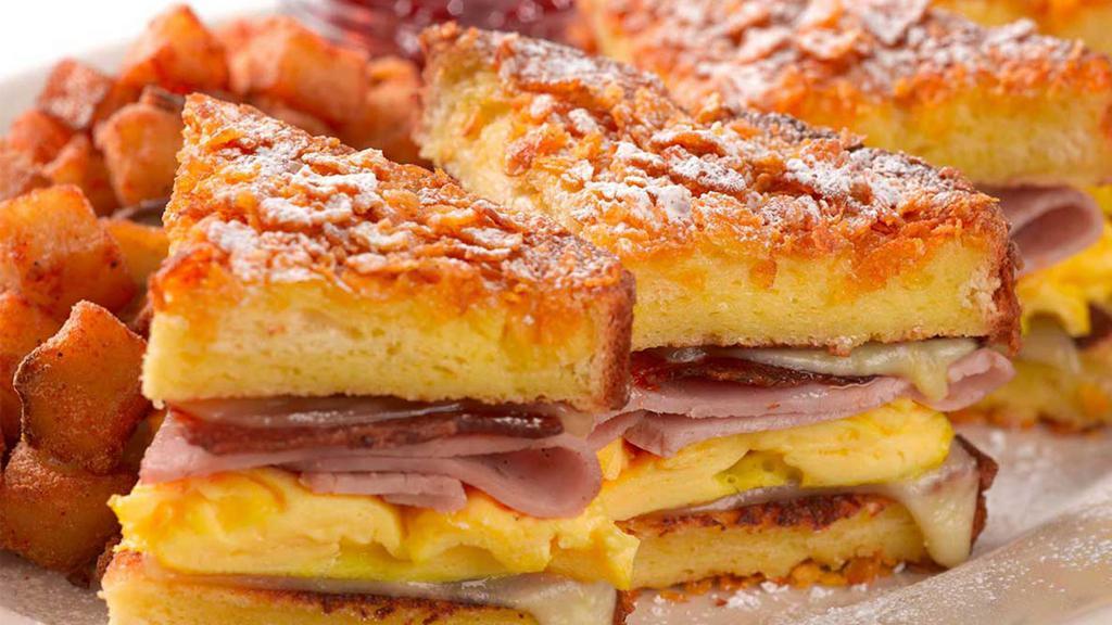 Monte Cristo Sandwich · Crunchy French Toast Stuffed with Bacon, Grilled Ham, Scrambled Eggs and Melted Swiss Cheese Dusted with Powdered Sugar and Served with Strawberry Preserves