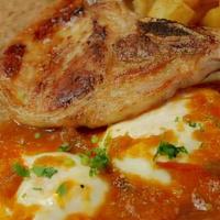 Chuletas Rancheras · Two pork chops, eggs, breakfast potatoes, and refried beans.