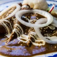 Enchiladas De Mole · Homemade corn tortillas stuffed with shredded chicken. Topped with mole, crema, and queso fr...