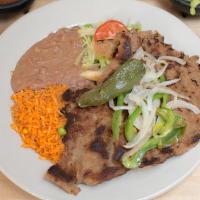 Milanesa De Res · Breaded steak served with rice and beans.