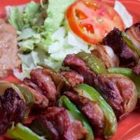 Brochetas · Fajita beef skewers, hickory bacon, purple onion, and peppers. Served with refried beans, Sp...