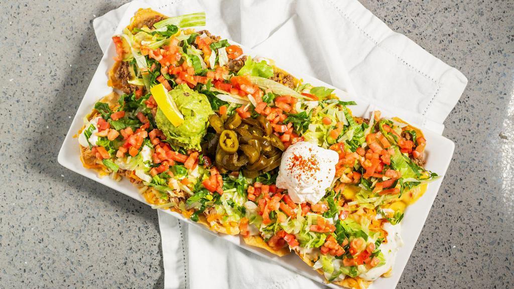 Borracho Nachos · Thick corn tortilla chips with refried beans, shredded chicken or picadillo beef, Jack-Cheddar cheese, topped with lettuce, tomatoes, jalapenos and two types of queso!
