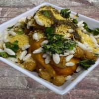 Samosa Chaat · Two of our house-made samosas topped with chickpea masala, cilantro tamarind chutney, chickp...