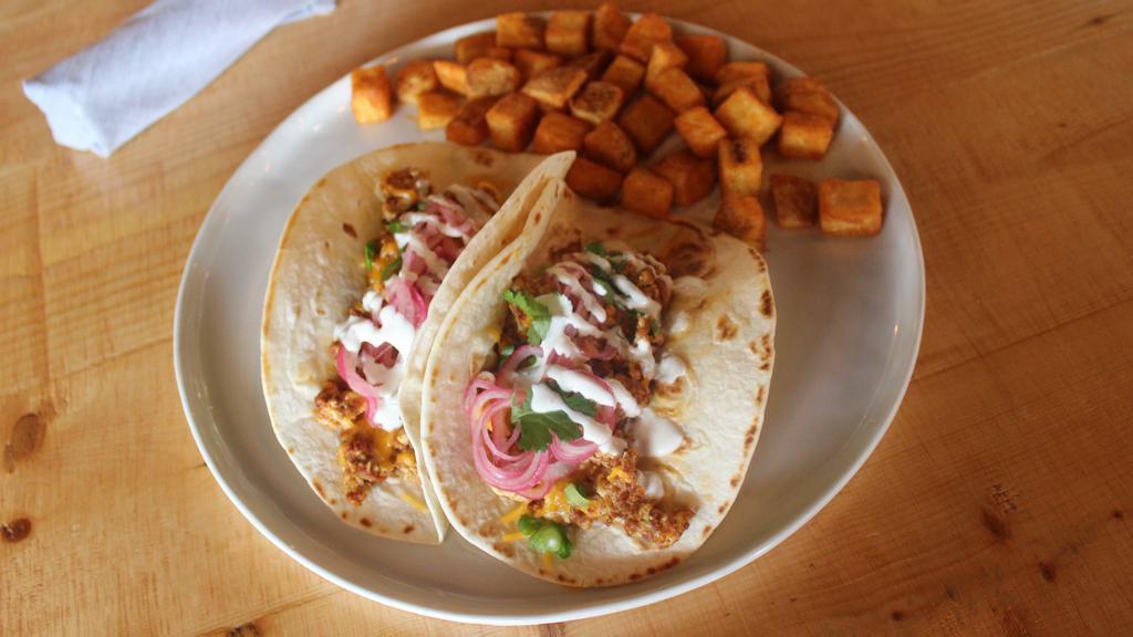 Chorizo Breakfast Taco · Beef chorizo, eggs, cheddar cheese, green onions, pickled red onions, cilantro, and crema. Served on 2 warm flour tortillas and a side of breakfast potatoes.
