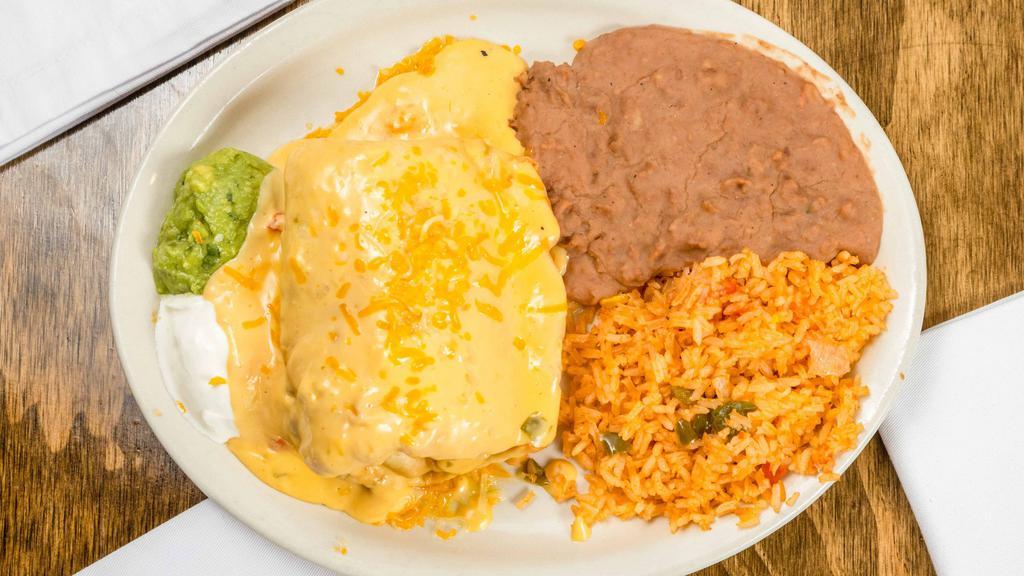 Chimichanga · EXTRA LARGE fried flour tortilla stuffed with mixed cheeses, taco meat or shredded chicken, topped with queso sauce or Xmas style, guacamole and sour cream side.  Served with Mexican rice and refried beans. 
*Add grilled chicken, steak or carnitas with additional price.