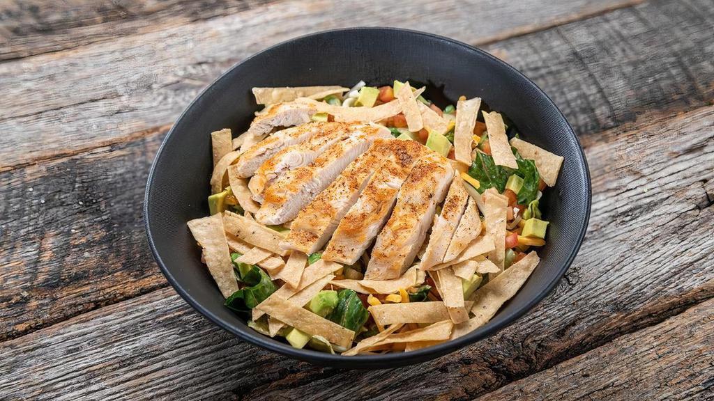 Southwest Grilled Chicken Salad · Piled high with diced avocado, corn, red & yellow onion, cilantro, tomato, bell pepper, and tossed in jalapeño ranch dressing. Topped with cheddar-jack cheese, tortilla strips, and grilled chicken breast seasoned with our ancho chili lime dry rub.