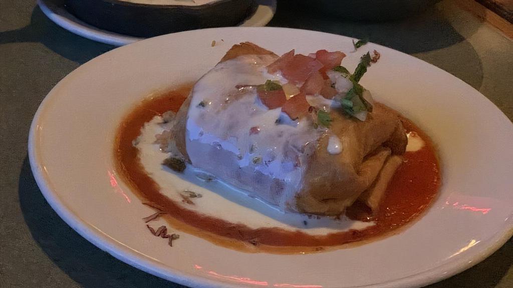 Chimichanga · A deep fried burrito stuffed with your choice of meat (chicken fajita, beef fajita, or brisket), cheese, rice, and pinto or black beans. Served on bed of tomato sauce. Topped with queso dip and garnished with pico de gallo.