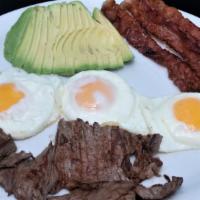 Complete Breakfast · One bistec with three over-easy eggs, bacon strips, and avocado.