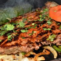 Texas T-Bone · Grilled T-Bone served over grilled onions and chile toreado on a hot skillet