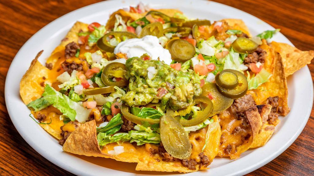 Stadium Nachos · Fresh tortilla chips smothered with re-friend beans, cheese, lettuce, pico De gallo, jalapeños, sour cream, and guacamole.