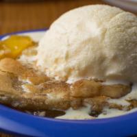 Peach Cobbler & Cream · Peach Cobbler served with a scoop of Blue Bell Homemade Vanilla ice cream on the side.