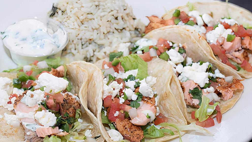 Atlantic Salmon Tacos · Four tacos filled with blackened Atlantic salmon, shredded lettuce, cilantro lime aioli, feta cheese, and pico de gallo. Served with a side of cilantro lime rice.