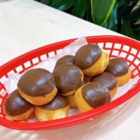 Chocolate Donut Holes (1 Dz) · A bag filled with 12 pieces of chocolate dipped donut holes.