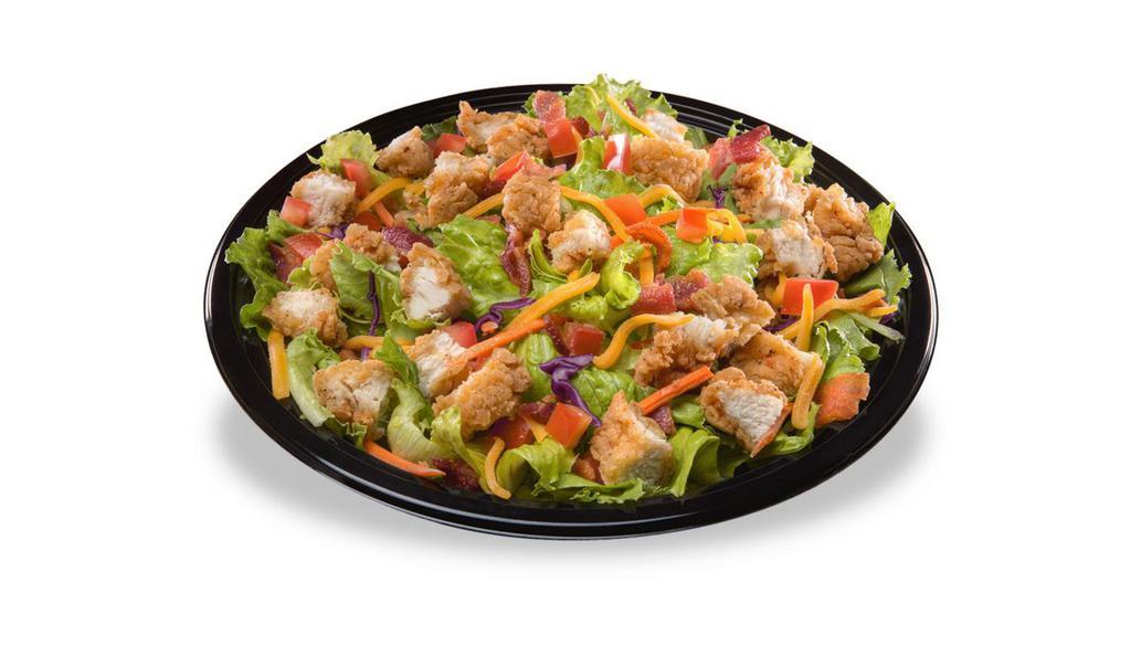 Crispy Chicken Salad · Our signature chicken strips, served hot and crispy, diced and placed on a crispy blend of romaine and iceberg lettuce. Topped with diced tomatoes, cheddar cheese, and hand chopped hickory smoked bacon. Served with honey mustard.
