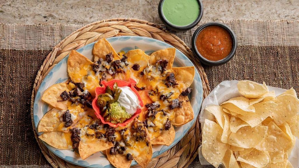 Fajita Nachos · Corn tortilla chips. topped with your choice of fajita, refried beans, and melted jack and cheddar cheese. Served with guacamole, sour cream and jalapeños.