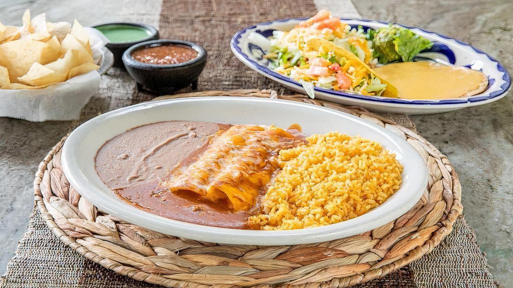 The Deluxe · Queso Chip, bean tostada, ground beef taco, 2 cheese enchiladas topped with Chile con carne, grated cheese, guacamole, and your choice of beans & rice.  (Refried beans and Mexican rice Default)
