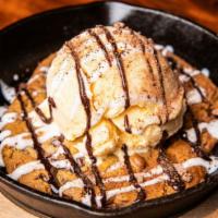 Cast Iron Chocolate Chip Cookie · Freshly baked chocolate chip cookie topped with vanilla ice cream and caramel sauce.