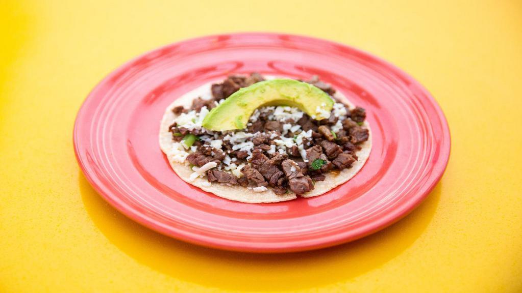 Taco Al Carbon · Certified Angus beef. Diced charbroiled fellas, green onions, cilantro, queso fresco, and sliced avocado.