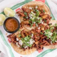 Tacos Al Pastor · Soft corn tacos filled with marinated pork, grilled onions and cilantro.