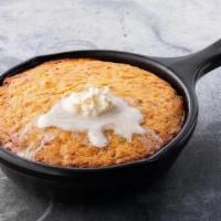 Skillet Cornbread · Scratch-made, honey sweetened cornbread, served warm in a skillet with melted honey butter .