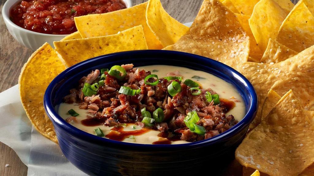 New! Brisket Queso · Our creamy, homemade green chile queso topped with smoked, shredded brisket, chopped green onions and drizzled in Dr Pepper BBQ sauce, served with warm, crunchy tortilla chips and our own freshly made salsa