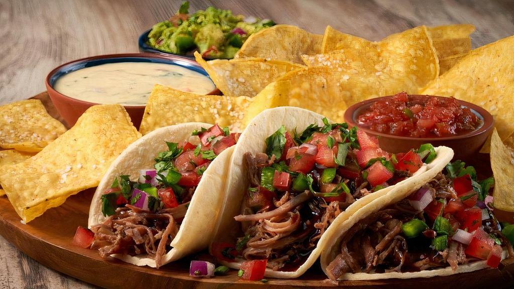 Brisket Street Tacos · Three warm tortillas filled with smoked brisket, Dr Pepper BBQ sauce, fresh pico de gallo, served with homemade green chile queso, our own freshly made guac and salsa, and warm, crunchy tortilla chips