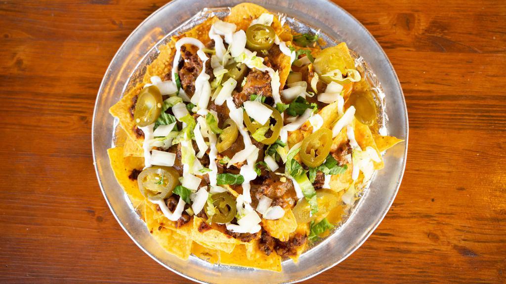 Chili Nachos · Warm Tortilla Chips covered with our House Made Chili, melted Cheddar Cheese, served with jalapeños, diced onions, sour cream. shredded lettuce and salsa.