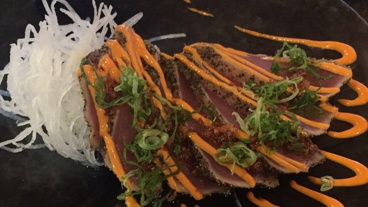Pepper Tuna Tataki · Thin slices of seared ahi tuna with cracked pepper crust on the outside, served in spicy mayo with roasted garlic and chopped green onions.