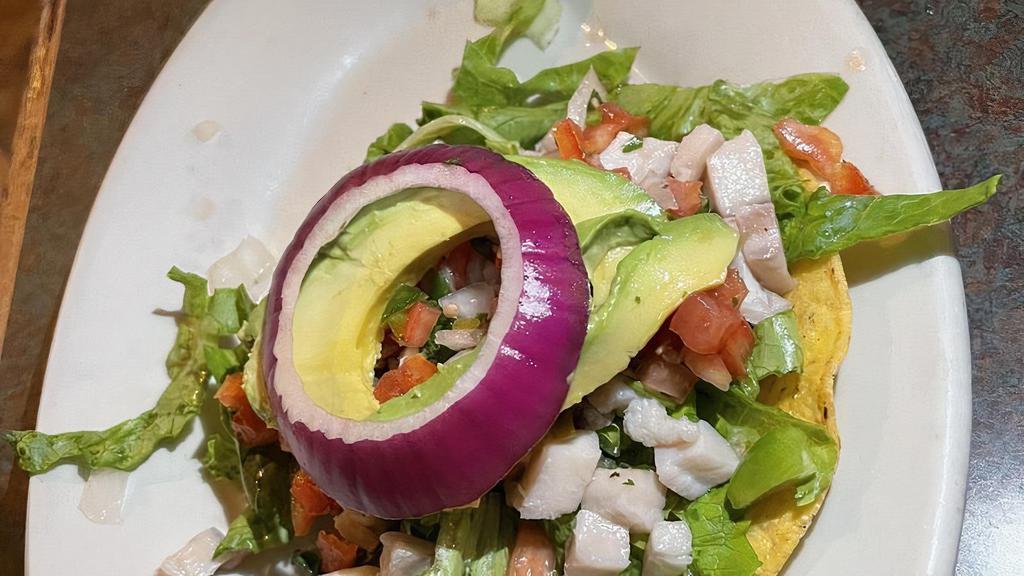 Ceviche Tostada · One single tostada topped with fish ceviche, lettuce, and diced avocado.