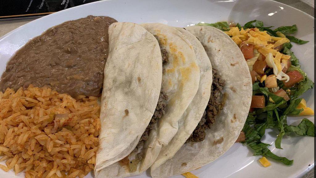 Tacos Al Carbon · Marinated and grilled beef and chicken breast sliced thin and rolled in a flour tortilla. Served with rice and bean soup, fresh guacamole, and pico de gallo.