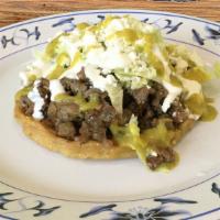 Sope With Guiso · Handmade tortilla with raised edges, beans, your choice of guiso, lettuce, sour cream, and q...