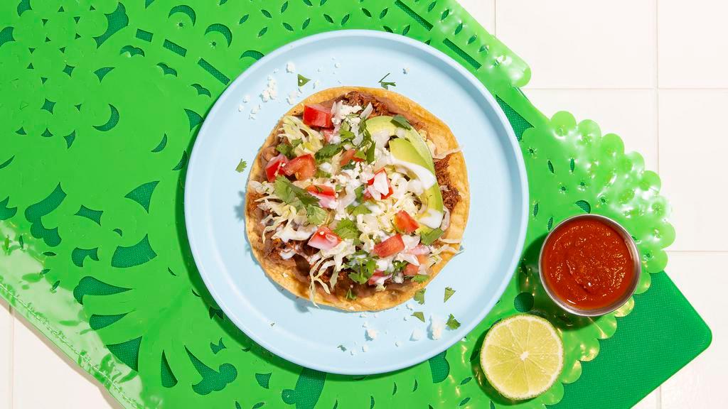 Tostada · Flat corn crisp topped with your choice of protein, cotija, lettuce, and tomato.
