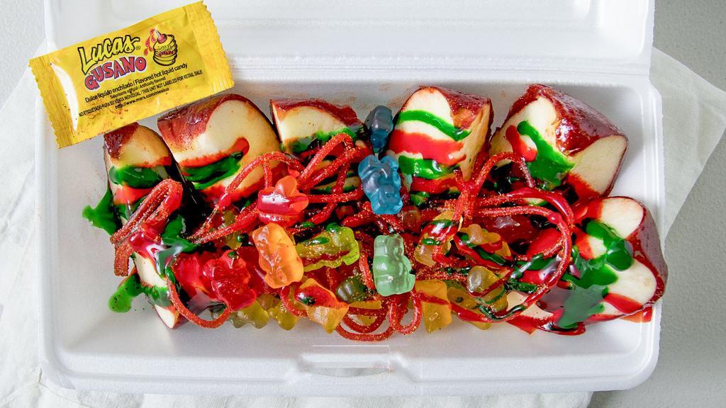 Manzana Loca · Crisp red apples covered in tamarindo candy cut up into slices with red and green chamoy, lucas, Japanese nuts, gummy bears, and salsagheti candy.