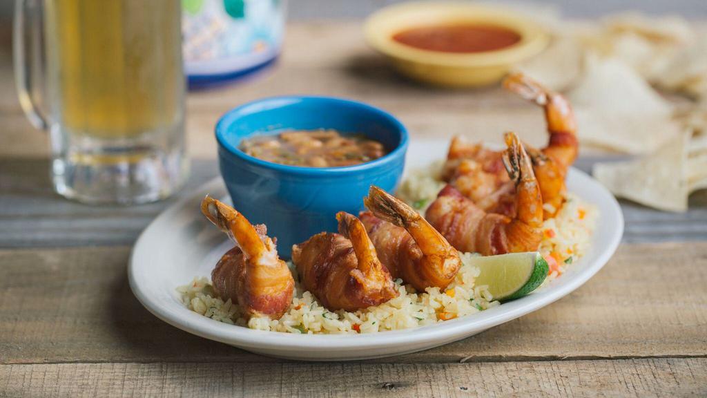 Shrimp Brochette · Six bacon-wrapped shrimp stuffed with jalapeños and Monterey Jack cheese deep-fried golden brown on a bed of vegetable rice with charro beans. Served with a side of garlic butter for dipping.