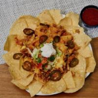 Nachos Ole · Seasoned beef or shredded chicken served on tortilla chips with chile con queso, refried bea...