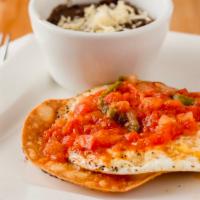 Huevos Rancheros · Crispy tostada with house made spicy ranchero sauce. Served with refried beans + hash brown ...