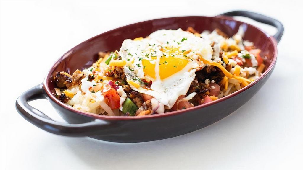 Sunny'S Skillet · Hash browns piled high with chorizo, cheese, crema, house salsas & a fried egg. Served with corn tortillas.
