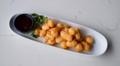 Cheese Curds · Crispy fried cheese curds, coated in tempura beer batter. Served with sweet jalapeño jam and Sriracha dipping sauce.
