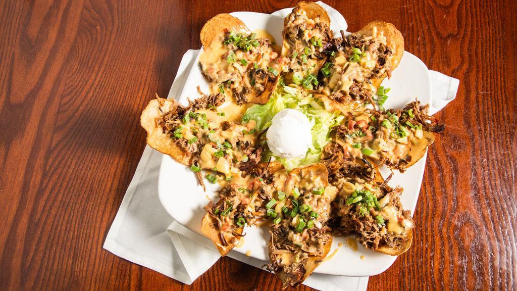 Brisket Chips · Hand cut potato chips topped with smoked brisket, smothered in queso and green onions.