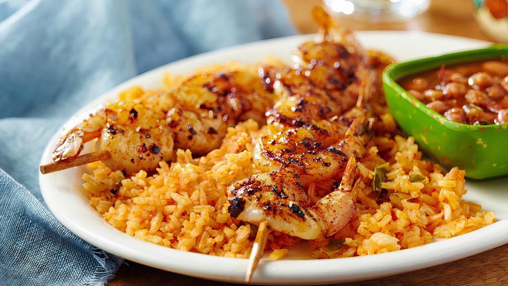 Shrimp En Fuego · Fire-grilled shrimp skewers glazed with our mix of garlic and chiles, served with rice and borracho beans.