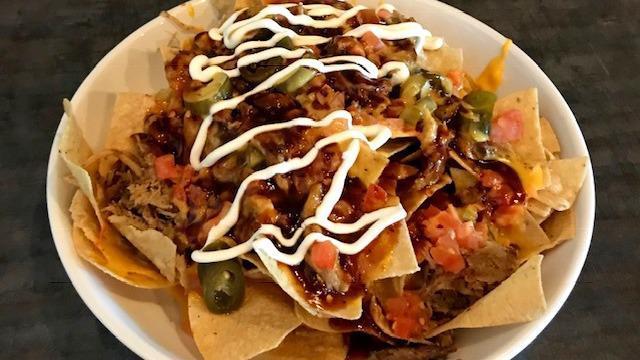 Mp Pulled Pork Nachos · Tortilla chips filled high and topped with tender shredder pork, spicy queso and cheddar cheese. Then we top it of with our sweet n spicy BBQ sauce, tomatoes, jalapenos and sour cream.